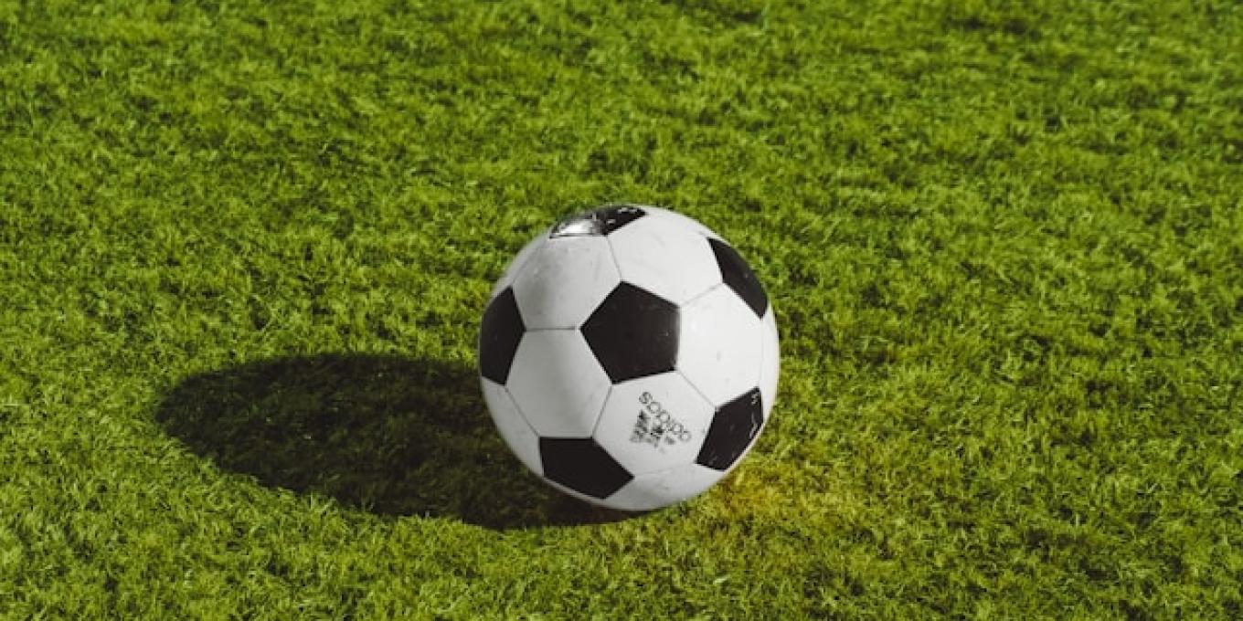 Soccer ball on green grass under sunlight.